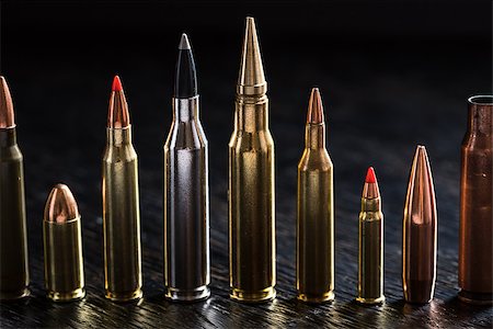 simsearch:400-04577380,k - Number of large-caliber ammunition of different caliber in one line on a dark textural wooden background. Studio shot. Fotografie stock - Microstock e Abbonamento, Codice: 400-08340613
