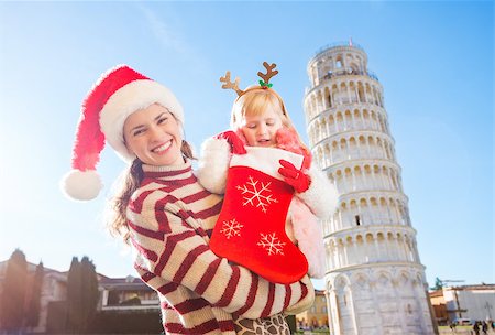 simsearch:400-08341864,k - Mother in Christmas hat holding daughter in funny reindeer antlers looking into Christmas sock for a gift. Leaning Tour of Pisa in background. They spending exciting Christmas time traveling Italy Fotografie stock - Microstock e Abbonamento, Codice: 400-08340901