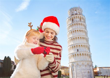 simsearch:400-08341864,k - Happy mother in Christmas hat and daughter wearing funny reindeer antlers checking photos on camera in front of Leaning Tour of Pisa, Italy. They spending exciting Christmas time traveling. Fotografie stock - Microstock e Abbonamento, Codice: 400-08340914