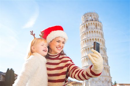 simsearch:400-08341864,k - Happy mother in Christmas hat and daughter wearing funny reindeer antlers taking selfies in front of Leaning Tour of Pisa, Italy. They spending exciting Christmas time traveling. Fotografie stock - Microstock e Abbonamento, Codice: 400-08340917