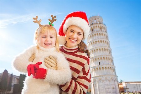 simsearch:400-08341864,k - Portrait of happy mother in Christmas hat and daughter wearing funny reindeer antlers standing in front of Leaning Tour of Pisa, Italy. They spending exciting Christmas time traveling. Fotografie stock - Microstock e Abbonamento, Codice: 400-08340918