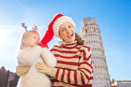 simsearch:400-08341864,k - Girl wearing funny reindeer antlers pulling Christmas hat from head of her smiling mother in front of Leaning Tour of Pisa, Italy. They spending exciting Christmas time traveling. Fotografie stock - Microstock e Abbonamento, Codice: 400-08340921
