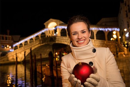 Happy elegant young woman in white coat holding Christmas Ball while standing in front of Rialto Bridge in the evening. She having Christmas time trip and enjoying stunning views of Venice, Italy Stock Photo - Budget Royalty-Free & Subscription, Code: 400-08341848