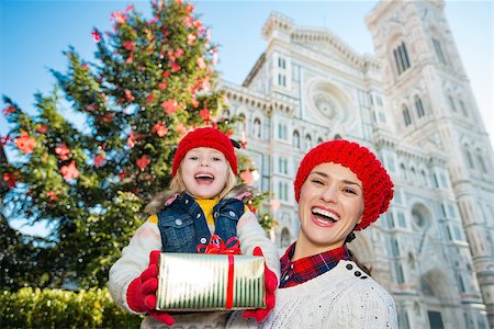 simsearch:400-08341864,k - Smiling mother and daughter showing gift box in front of Christmas tree near Duomo in Florence, Italy. Modern family enjoying carousel of Christmas time events in heart of the Renaissance. Fotografie stock - Microstock e Abbonamento, Codice: 400-08341875