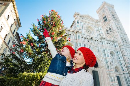 simsearch:400-08341864,k - Smiling mother and daughter pointing on something while standing near Christmas tree and Duomo in Florence, Italy. Modern family enjoying carousel of Christmas time events in heart of the Renaissance. Fotografie stock - Microstock e Abbonamento, Codice: 400-08341871