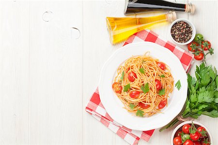 Spaghetti pasta with tomatoes and parsley on wooden table. Top view with copy space Stock Photo - Budget Royalty-Free & Subscription, Code: 400-08343185