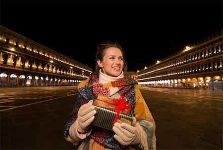 simsearch:400-08344334,k - Excitement of Christmas time and allure of long-time favourite Venice, Italy. Happy woman holding Christmas gift box while standing on Piazza San Marco in the evening Stock Photo - Budget Royalty-Free & Subscription, Code: 400-08343469