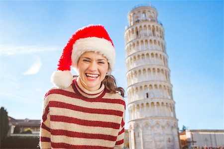simsearch:400-08344334,k - Young, itching from energy and searching for excitement. I'm going to Christmas trip to Italy. It is a no-brainer. Portrait of happy woman in Santa hat in front of Leaning Tour of Pisa. Stock Photo - Budget Royalty-Free & Subscription, Code: 400-08343848