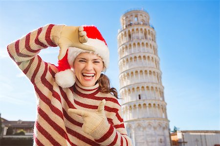 simsearch:400-08344334,k - Young, itching from energy and searching for excitement. I'm going to Christmas trip to Italy. It is a no-brainer. Smiling woman in Santa hat framing with hands in front of Leaning Tour of Pisa. Stock Photo - Budget Royalty-Free & Subscription, Code: 400-08343849