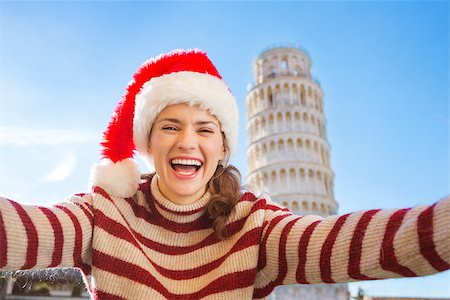 simsearch:400-08344334,k - Young, itching from energy and searching for excitement. I'm going to Christmas trip to Italy. It is a no-brainer. Happy woman in Santa hat taking selfie in front of Leaning Tour of Pisa. Stock Photo - Budget Royalty-Free & Subscription, Code: 400-08343853