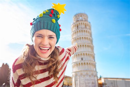 simsearch:400-08344334,k - Young, itching from energy and searching for excitement. I'm going to Christmas trip to Italy. It is a no-brainer. Happy woman in Christmas tree hat pointing on Leaning Tour of Pisa Stock Photo - Budget Royalty-Free & Subscription, Code: 400-08343866
