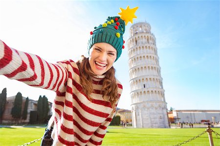 simsearch:400-08344334,k - Young, itching from energy and searching for excitement. I'm going to Christmas trip to Italy. It is a no-brainer. Happy woman in Christmas tree hat taking selfie in front of Leaning Tour of Pisa Stock Photo - Budget Royalty-Free & Subscription, Code: 400-08343862