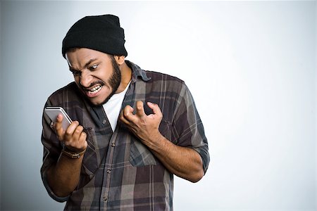 denovan (artist) - Young mixed race man with beard standing on grey background. Angry young man screaming at mobile phone Foto de stock - Super Valor sin royalties y Suscripción, Código: 400-08376736