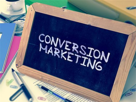 Conversion Marketing Handwritten by White Chalk on a Blackboard. Composition with Small Chalkboard on Background of Working Table with Office Folders, Stationery, Reports. Blurred, Toned Image. Stock Photo - Budget Royalty-Free & Subscription, Code: 400-08377977