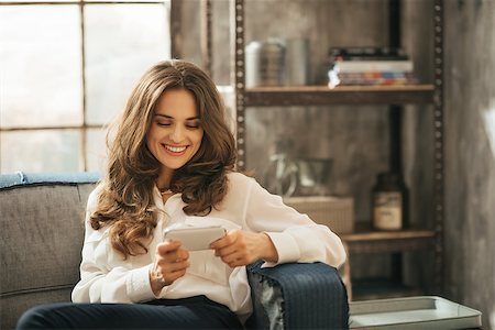 simsearch:400-08054469,k - Stylish brunet woman is playing with smartphone sitting on divan in loft apartment Stock Photo - Budget Royalty-Free & Subscription, Code: 400-08378118