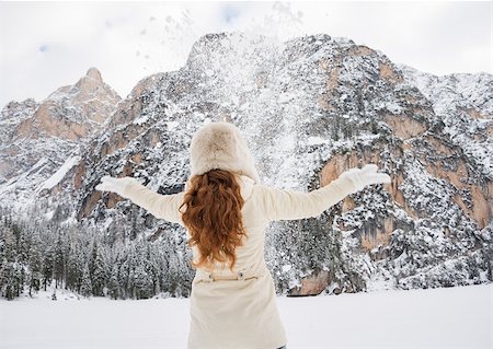 Magical mix of winter season and mountain landscape create the perfect mood. Seen from behind young woman in white coat and fur hat throwing snow outdoors Stock Photo - Budget Royalty-Free & Subscription, Code: 400-08378163