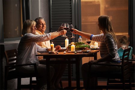 Family dinner outdoor in the backyard in quiet evening. Young woman and senior parents toasting with wine while child playing games Stock Photo - Budget Royalty-Free & Subscription, Code: 400-08378344