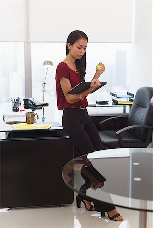 female business woman holding ball - Office worker leaning on desk. The woman reads an email on tablet computer and holds an anti-stress yellow ball. She feels stressed and nervous Stock Photo - Budget Royalty-Free & Subscription, Code: 400-08378892