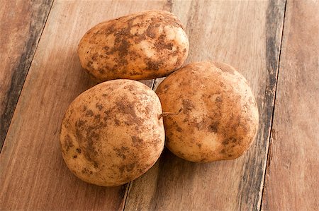 simsearch:6113-08985952,k - Close up Three Unwashed Fresh Potatoes on Top of a Wooden Table. Photographie de stock - Aubaine LD & Abonnement, Code: 400-08370703