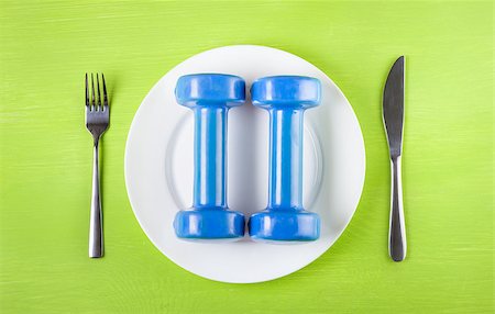 simsearch:640-01356052,k - The concept of a healthy lifestyle, diet, sports, weight loss, healthy diet. Dumbbells on a plate, knife, fork, top view, closeup Photographie de stock - Aubaine LD & Abonnement, Code: 400-08371156