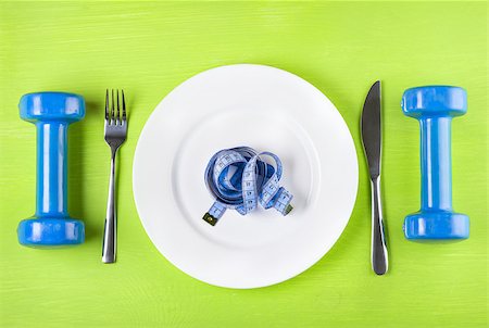 simsearch:640-01356052,k - The concept of a healthy lifestyle, diet, sports, weight loss, anti-obesity, exercise, healthy diet.  Centimeter on a plate, knife, dumbbells and fork, top view, closeup Photographie de stock - Aubaine LD & Abonnement, Code: 400-08371157