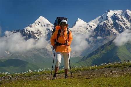 simsearch:877-08026622,k - Woman (backpacker)  with sunglasses and sticks against mountains covered with snow background. Tourist is situated on alpine meadow. Tviber mount is in the left part of image. Stock Photo - Budget Royalty-Free & Subscription, Code: 400-08371923