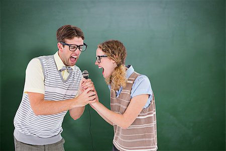 simsearch:400-08380794,k - Geeky hipster couple singing into a microphone against green chalkboard Stockbilder - Microstock & Abonnement, Bildnummer: 400-08380650