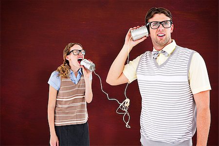 Geeky hipster couple speaking with tin can phone  against desk Stock Photo - Budget Royalty-Free & Subscription, Code: 400-08380793