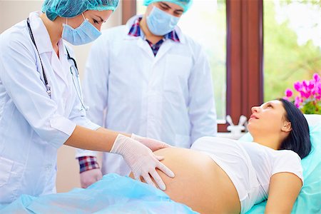 doctor palpates the abdomen of pregnant woman during childbirth Stock Photo - Budget Royalty-Free & Subscription, Code: 400-08400301