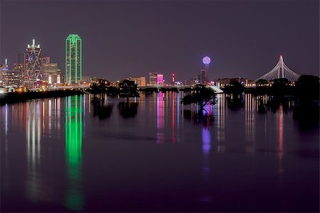 dallas - Long exposure photo of the lights of the Dallas, Texas skyline reflecting on the flooded Trinity River with trees in the river silhouetted by the glowing reflection.  Photographed from the Hampton Street Bridge. May 31, 2015, Photography by Stretch. Photographie de stock - Aubaine LD & Abonnement, Code: 400-08401225