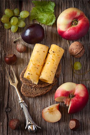 simsearch:400-08074810,k - Picnic nosh. Delicious cheese on a rye bread with fruit and nuts on a wooden board. Photographie de stock - Aubaine LD & Abonnement, Code: 400-08402597