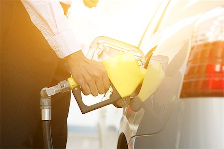 Close up business man pumping gasoline fuel in car at gas station, golden sunlight background. Foto de stock - Super Valor sin royalties y Suscripción, Código: 400-08402618