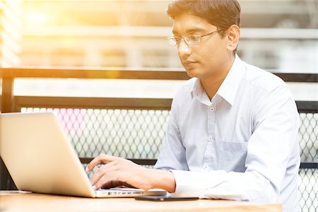 Candid Asian Indian businessman using laptop computer, modern building with golden sunlight at background. Stock Photo - Budget Royalty-Free & Subscription, Code: 400-08402622