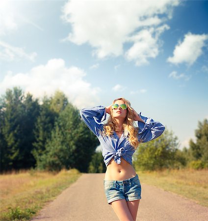 simsearch:400-08430017,k - Street Style Woman in Eyewear Looking Up to the Sky with Hands behind Head. Hipster Girl Walking on Country Road. Toned Photo with Copy Space. Stock Photo - Budget Royalty-Free & Subscription, Code: 400-08403174