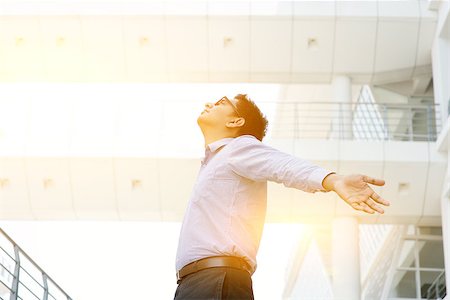 Business freedom concept. Asian businessman arms outstretched enjoying the morning breeze, morning sunlight and modern office as background. Stock Photo - Budget Royalty-Free & Subscription, Code: 400-08403626