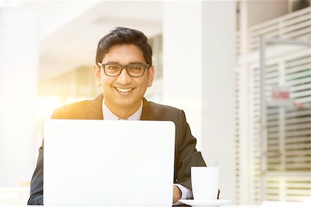 Asian Indian business people using a laptop or notebook computer at cafe, with a cup of coffee. India male business man, modern building with beautiful golden sunlight as background. Stock Photo - Budget Royalty-Free & Subscription, Code: 400-08403635