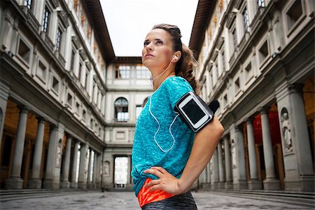 simsearch:400-08022064,k - Now it is time to invest in your body and no matter you are at hometown or traveling. Young sporty female with headset staying in front of Uffizi gallery and listening music Photographie de stock - Aubaine LD & Abonnement, Code: 400-08414767