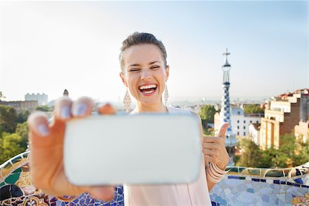 simsearch:400-08415527,k - Refreshing promenade in unique Park Guell style in Barcelona, Spain. Portrait of smiling young woman showing thumbs up and taking selfie with smartphone while in Park Guell, Barcelona, Spain Stock Photo - Budget Royalty-Free & Subscription, Code: 400-08415547