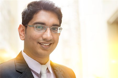 Close up portrait of handsome Asian Indian business man smiling, outside modern office building block, beautiful golden sunlight at background. Stock Photo - Budget Royalty-Free & Subscription, Code: 400-08427558