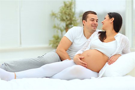 the man leaned against  to the baby bump of his pregnant wife, who is lying on the bed Photographie de stock - Aubaine LD & Abonnement, Code: 400-08428798