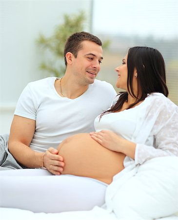 the man leaned against  to the baby bump of his pregnant wife, who is lying on the bed Photographie de stock - Aubaine LD & Abonnement, Code: 400-08428800