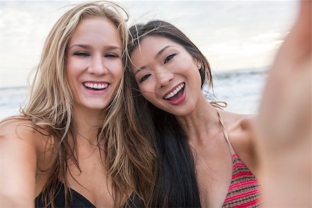 simsearch:400-08291180,k - Two young women girls, one Asian Chinese, one blond, wearing bikinis on a beach, laughing taking selfie photograph with digital camera Foto de stock - Royalty-Free Super Valor e Assinatura, Número: 400-08430063