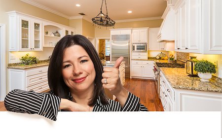 Hispanic Woman with Thumbs Up In Custom Kitchen Interior Leaning on White. Stock Photo - Budget Royalty-Free & Subscription, Code: 400-08431542