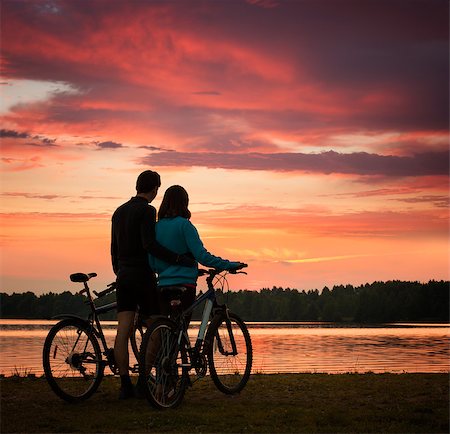 Romantic Couple with Bicycles Watching Sunset. Summer Nature Background with Beautiful Clouds, Sky and River. Active Leisure Concept. Fotografie stock - Microstock e Abbonamento, Codice: 400-08431554