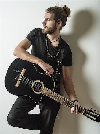 shadow acoustic guitar - Photo of a young attractive man with long hair and beard leaning against the wall holding an acoustic guitar. Stock Photo - Budget Royalty-Free & Subscription, Code: 400-08431954