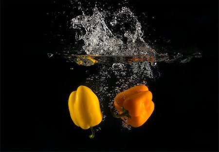 View of sweet peppers dropping into water on black background. Foto de stock - Royalty-Free Super Valor e Assinatura, Número: 400-08432185