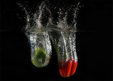 View of sweet peppers dropping into water on black background. Foto de stock - Royalty-Free Super Valor e Assinatura, Número: 400-08432186