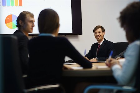 simsearch:400-05009097,k - Group of business people meeting in corporate conference room, smiling during a presentation. The coworkers are examining charts and slides on a big TV monitor Stock Photo - Budget Royalty-Free & Subscription, Code: 400-08433039
