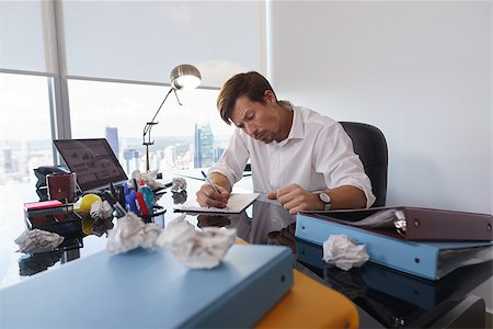 paper mistake - Corporate manager in modern office tries to write a job letter. The man is frustrated and keeps on screwing paper on desk Stock Photo - Budget Royalty-Free & Subscription, Code: 400-08433105