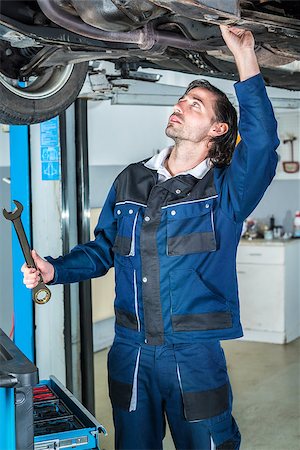 Portrait of a young male mechanic repairing a lifted car with a  big wrench Stock Photo - Budget Royalty-Free & Subscription, Code: 400-08433271